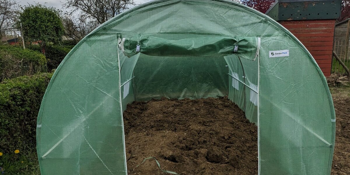 Installation d'une serre tunnel Gardenway ancrée dans le sol, avec structure enterrée pour respecter la hauteur maximale et améliorer la stabilité.